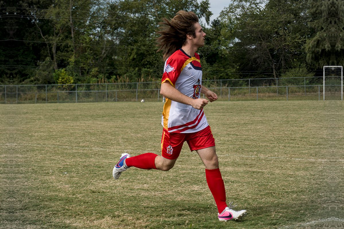 Soccer player in a red and white kit running across the field